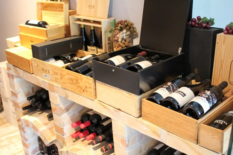 Caixas de madeira com garrafas de vinho sobre a estante de tijolos da adega da Taberna Ibérica