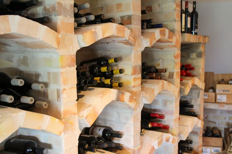 Garrafas de vinho deitadas nos nichos de tijolo da adega da Taberna Ibérica