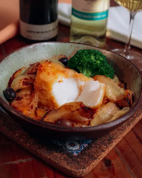 Posta de bacalhau com cebolas, batatas e brócolis